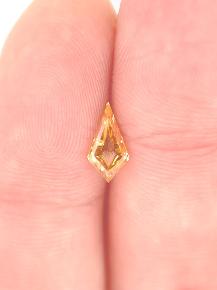 Loose kite-shaped champagne diamond with step cut resting on fingers to show scale