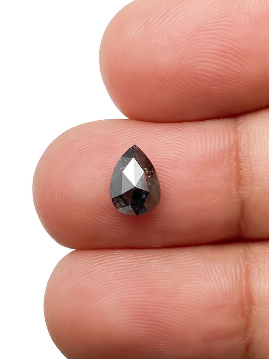 sustainable lab-grown pear shaped salt pepper diamond between fingers for scale