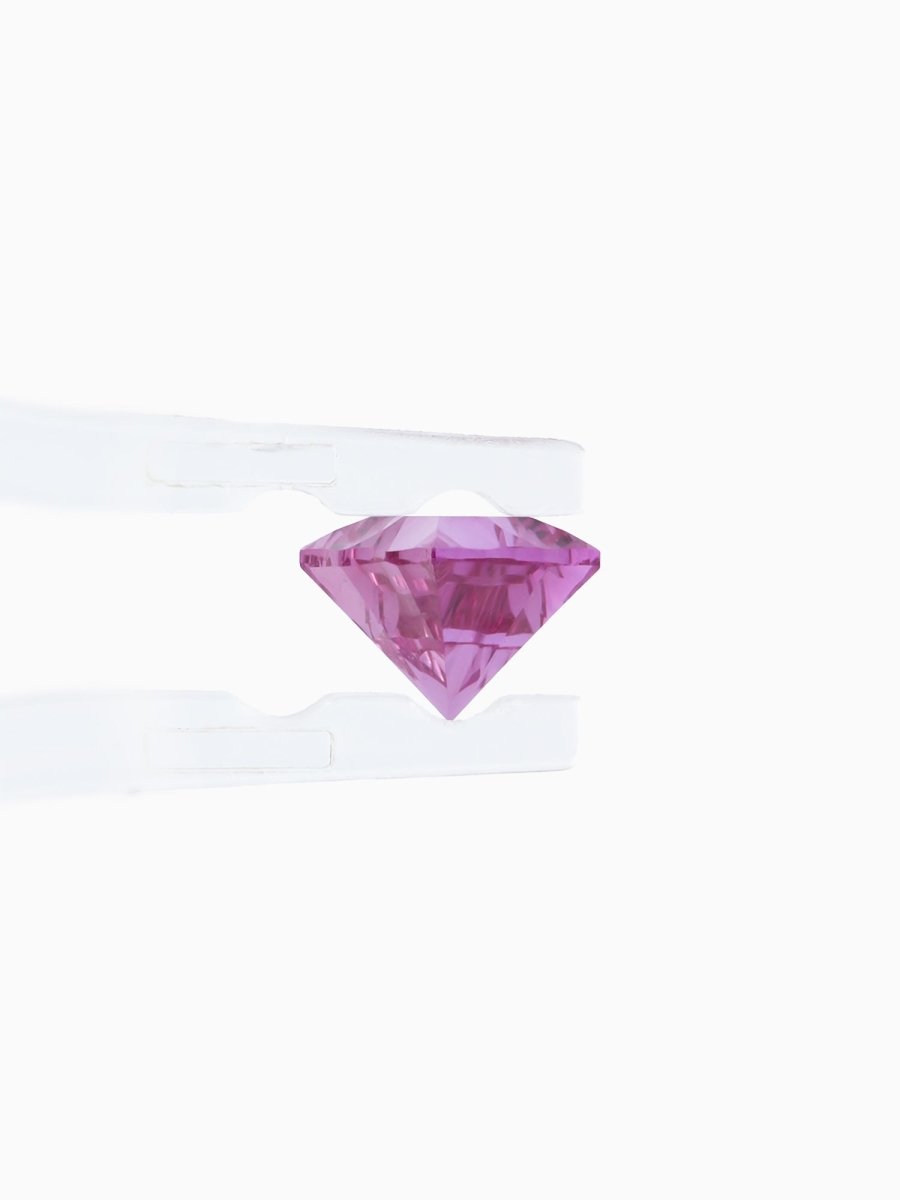 profile of burgundy sapphire held by tweezers on white background