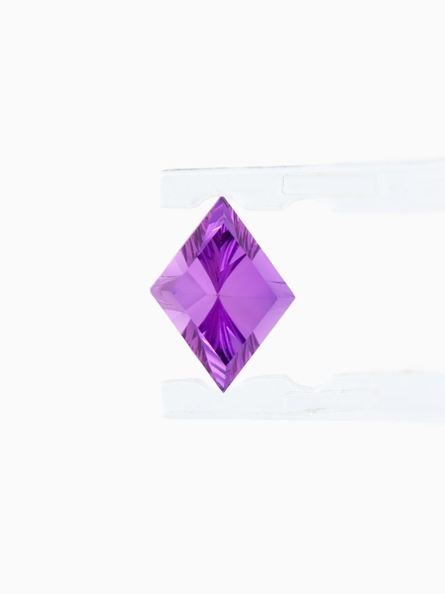 face view of designer cut purple kite sapphire held between tweezers on a white background