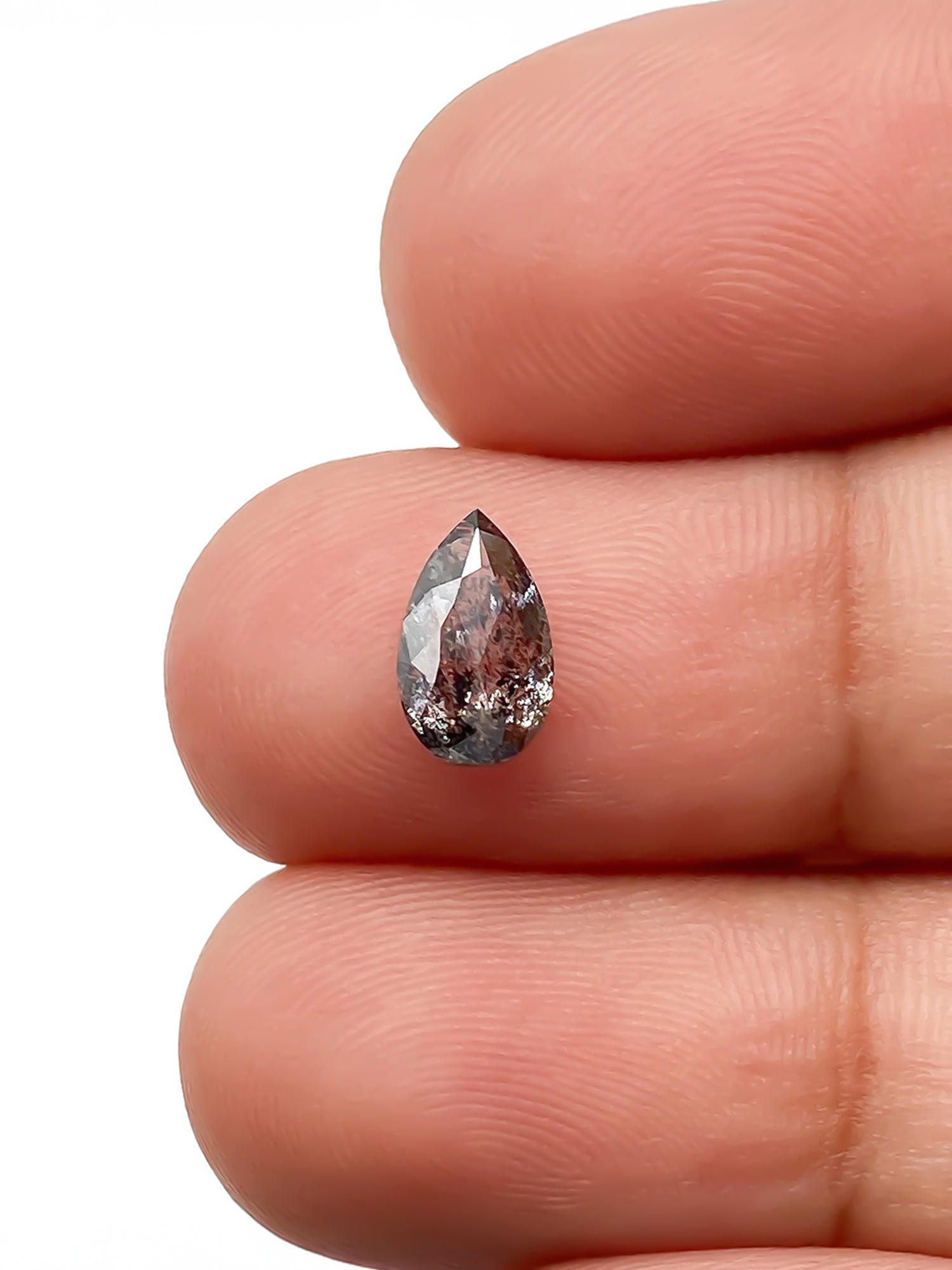 sustainable lab-grown pear shaped salt pepper diamond between fingers for scale