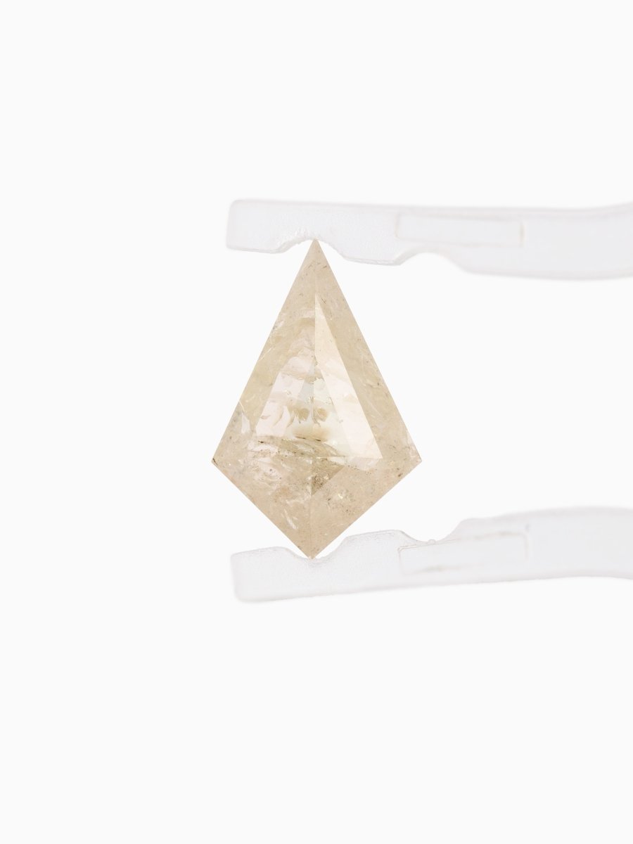 Face view of loose kite-shaped yellow salt and pepper diamond with white inclusions, step cut, held in tweezers
