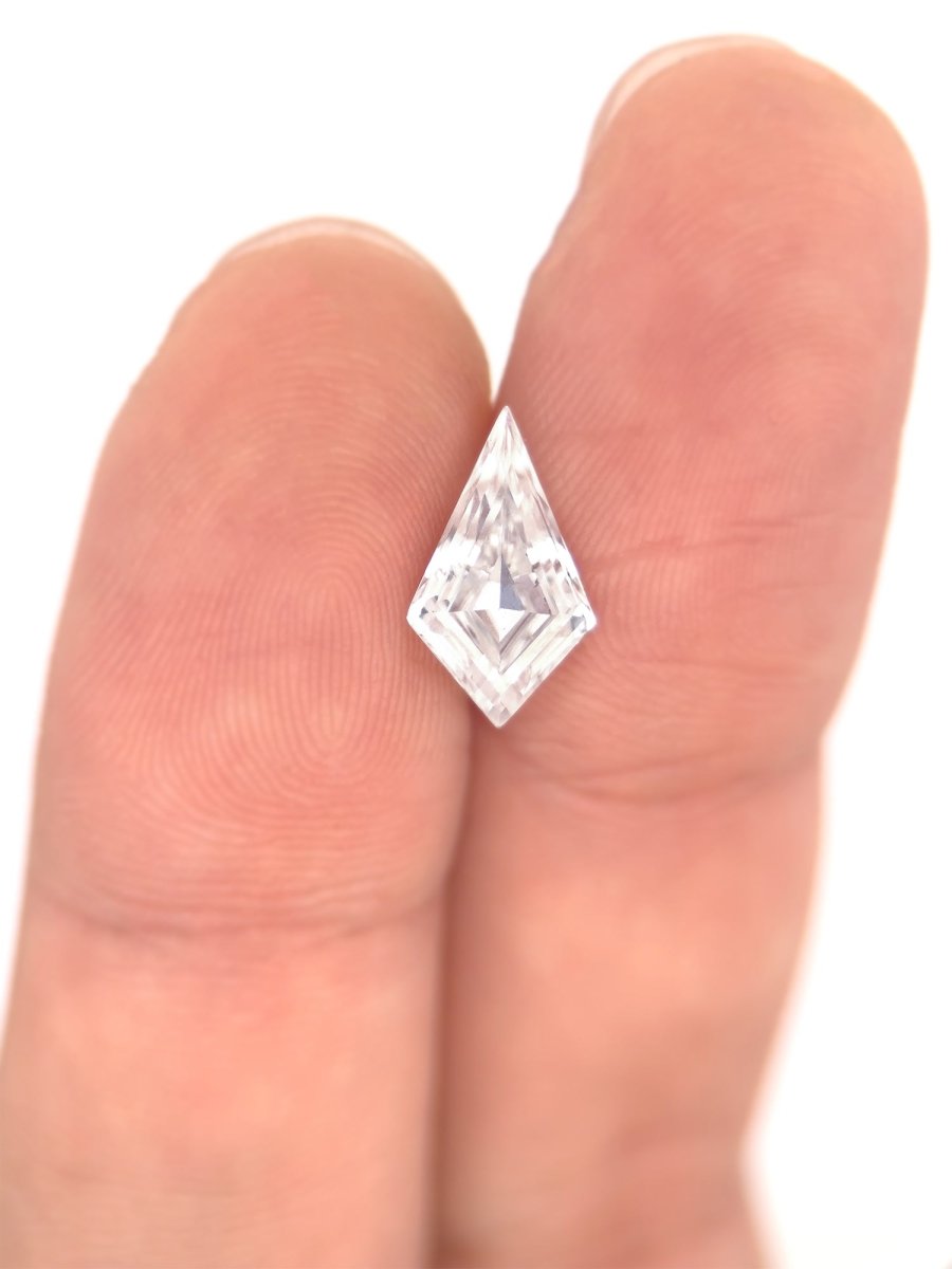 Top view of loose lab-grown kite shaped moissanite gemstone on finger, showing scale, sustainable and conflict-free