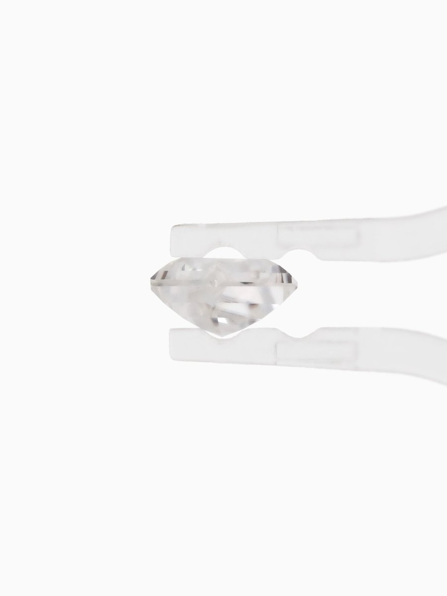 profile view of loose lab-grown kite moissanite gemstone held by tweezers, sustainable and conflict-free