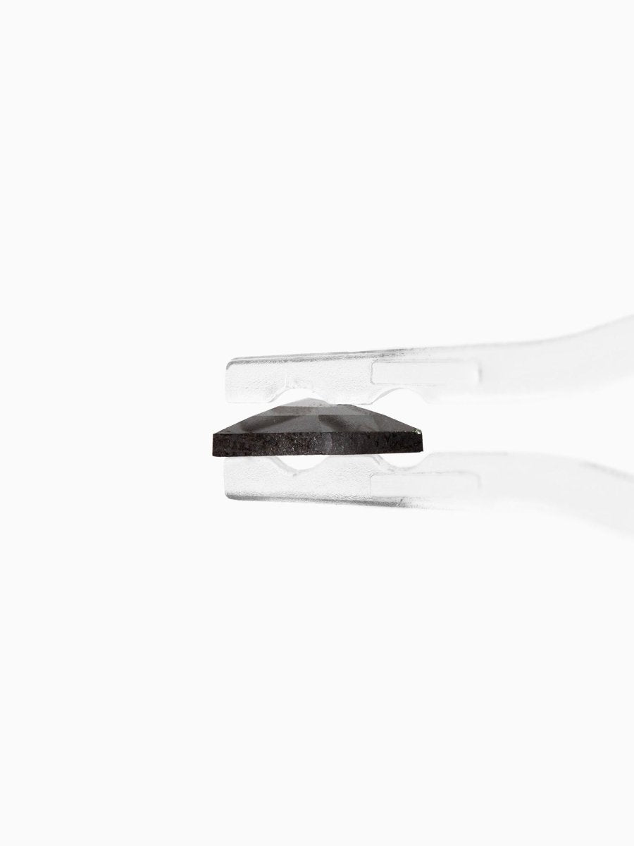 profile view of loose lab-grown hexagon salt pepper diamond gemstone held by tweezers