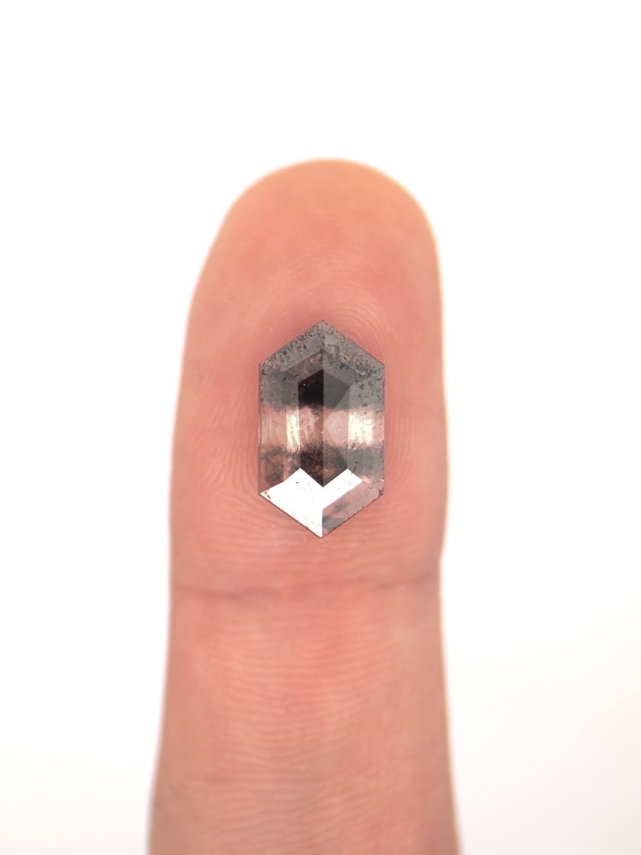 face view of loose lab-grown hexagon salt pepper diamond gemstone on finger for scale