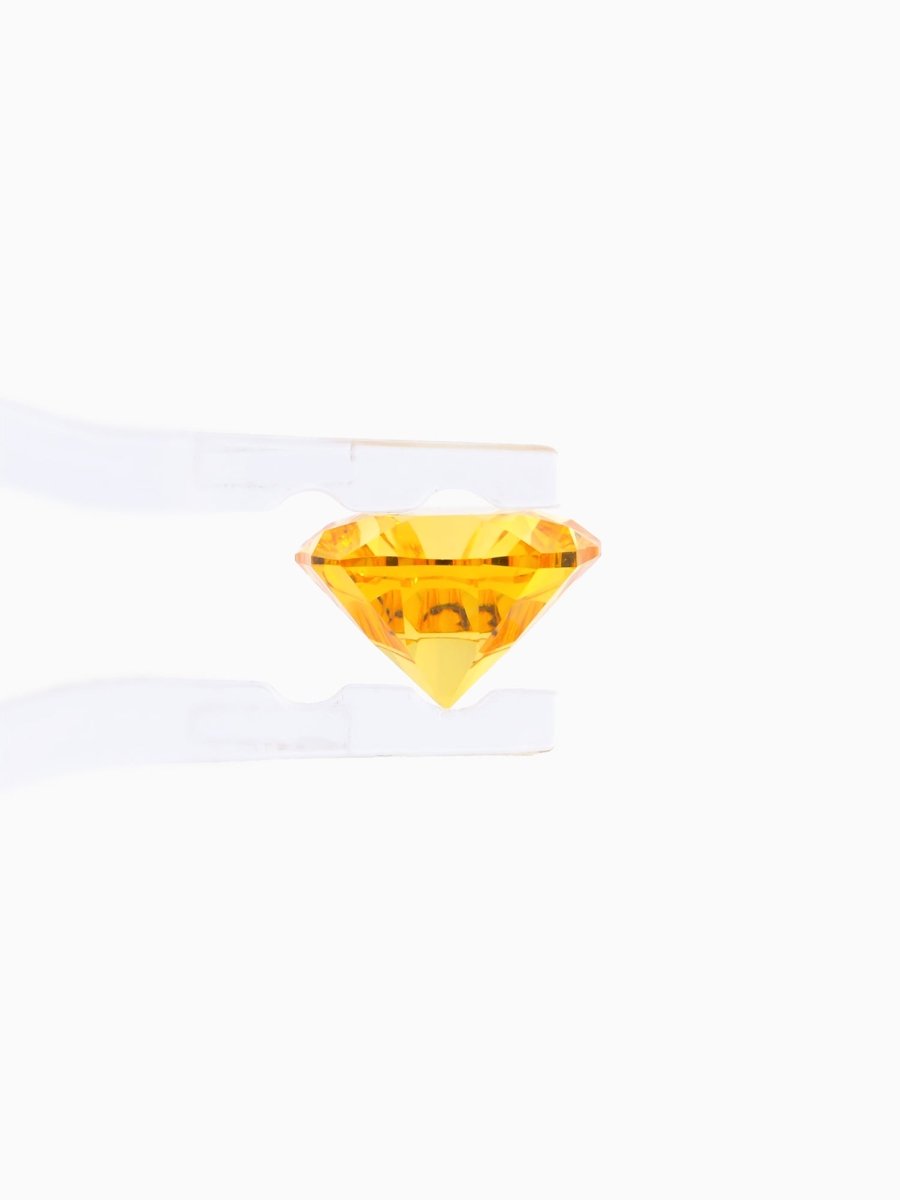 profile of yellow sapphire held by tweezers on white background