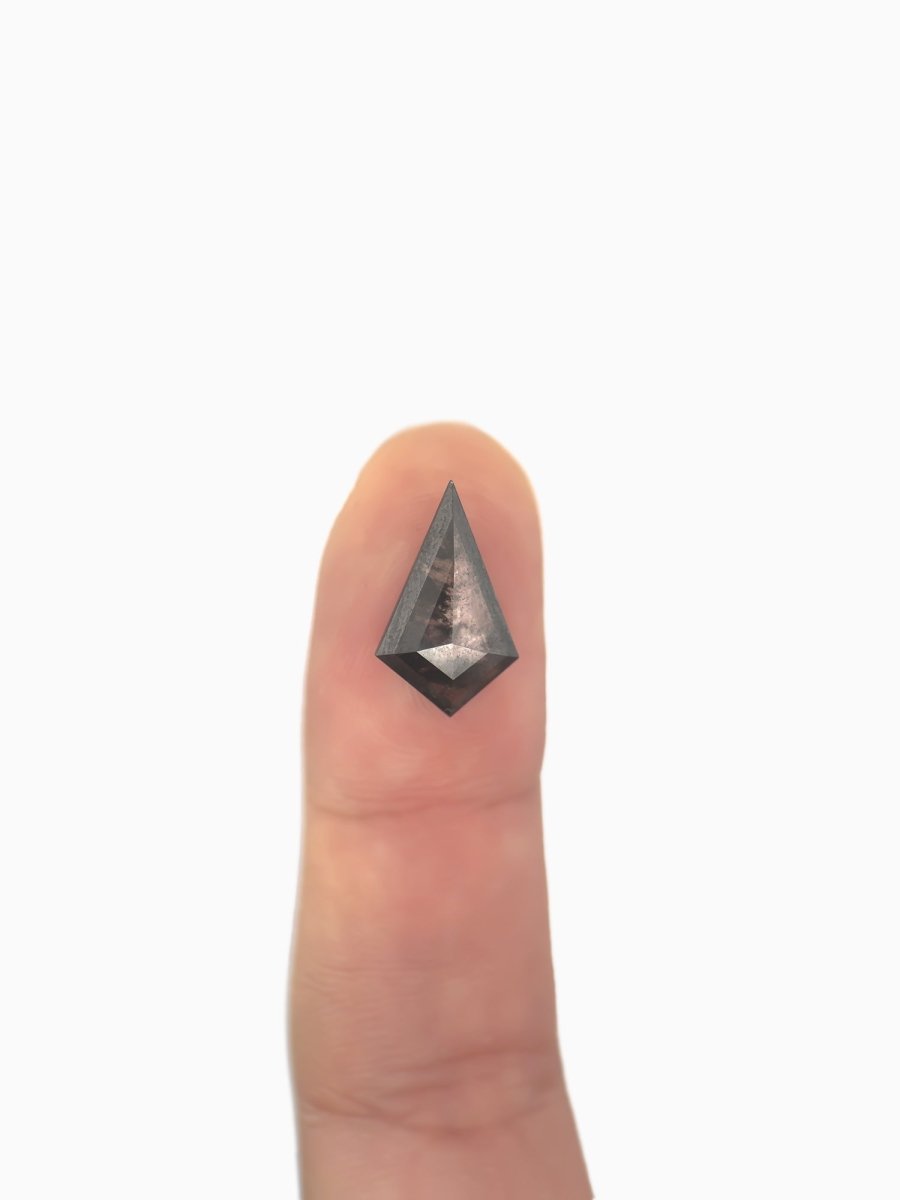 loose lab-grown kite salt pepper diamond gemstone on fingertip for scale