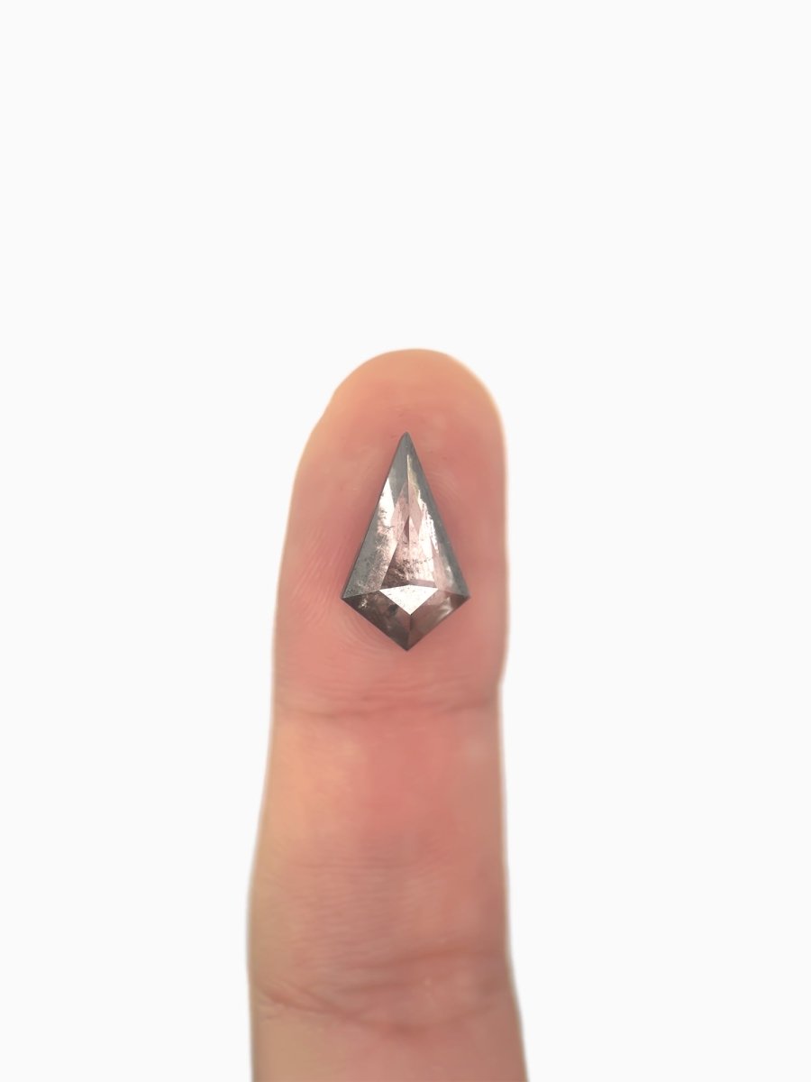 loose lab-grown kite salt pepper diamond gemstone on fingertip for scale
