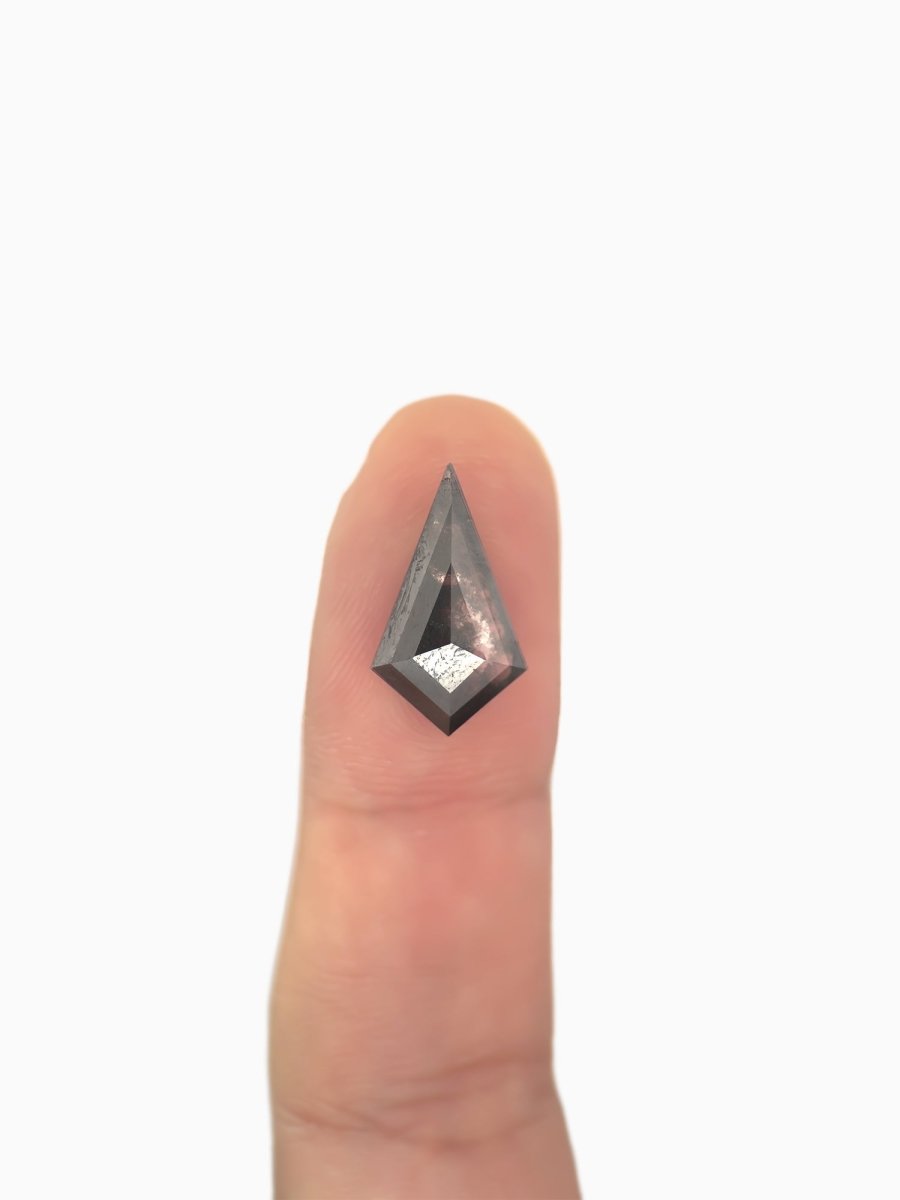 loose lab-grown kite salt pepper diamond gemstone on fingertip for scale