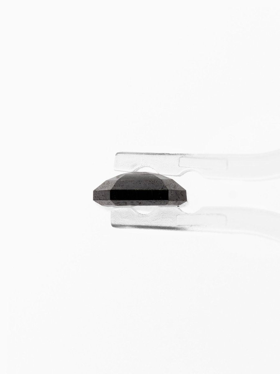 profile view of loose lab-grown emerald-cut salt pepper diamond gemstone held by tweezers