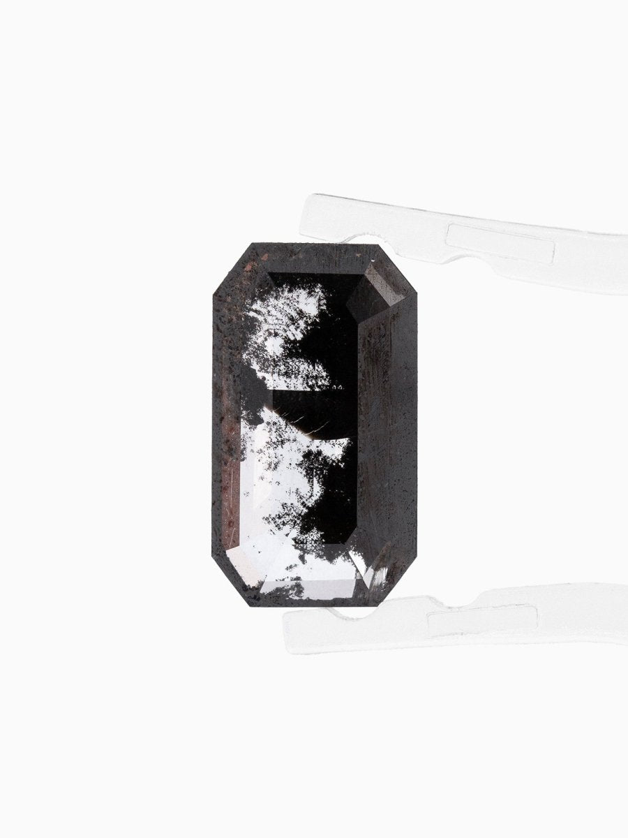 face view of loose lab-grown emerald-cut salt pepper diamond gemstone held by tweezers