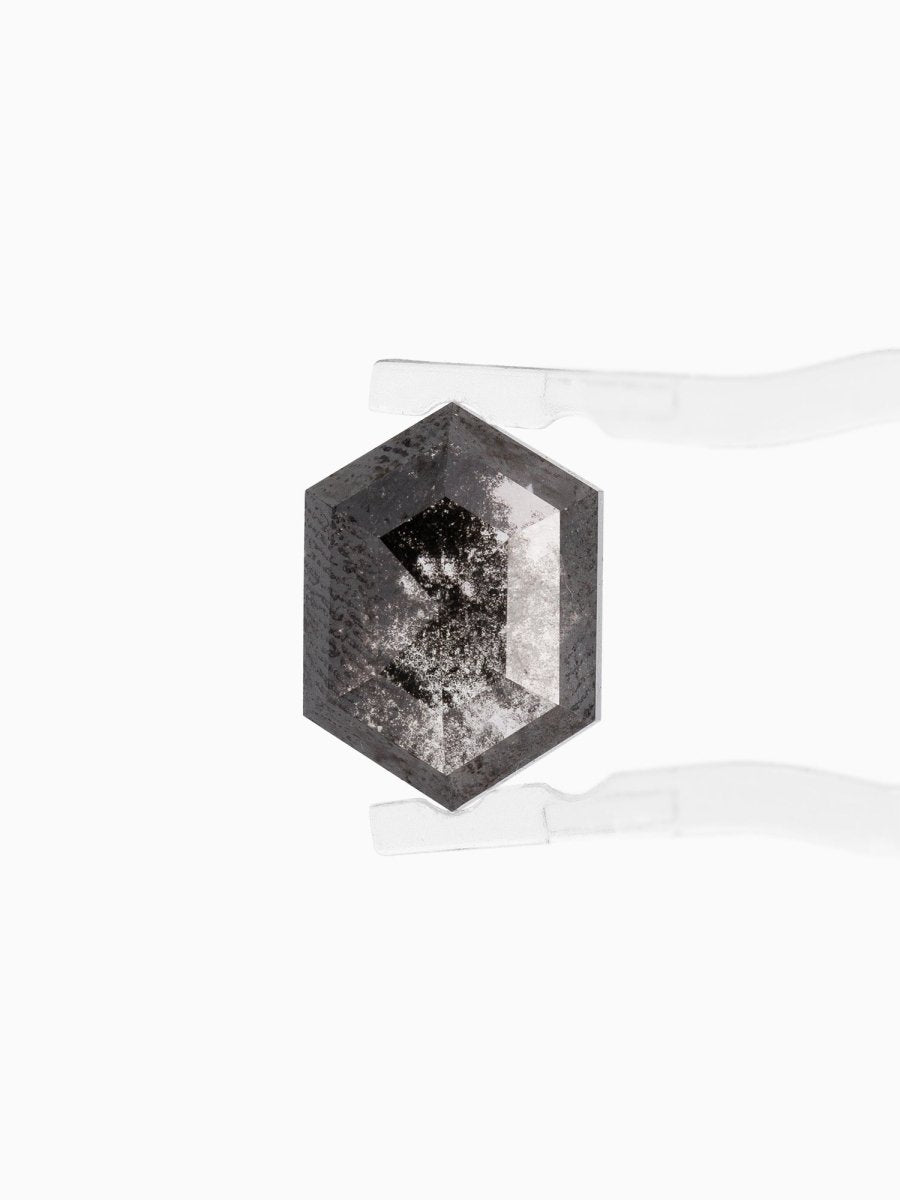 face view of loose lab-grown hexagon salt pepper diamond gemstone held by tweezers