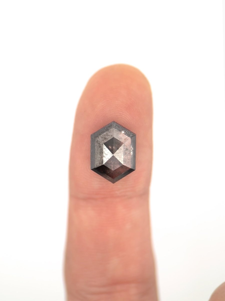 face view of loose lab-grown hexagon salt pepper diamond gemstone on finger for scale
