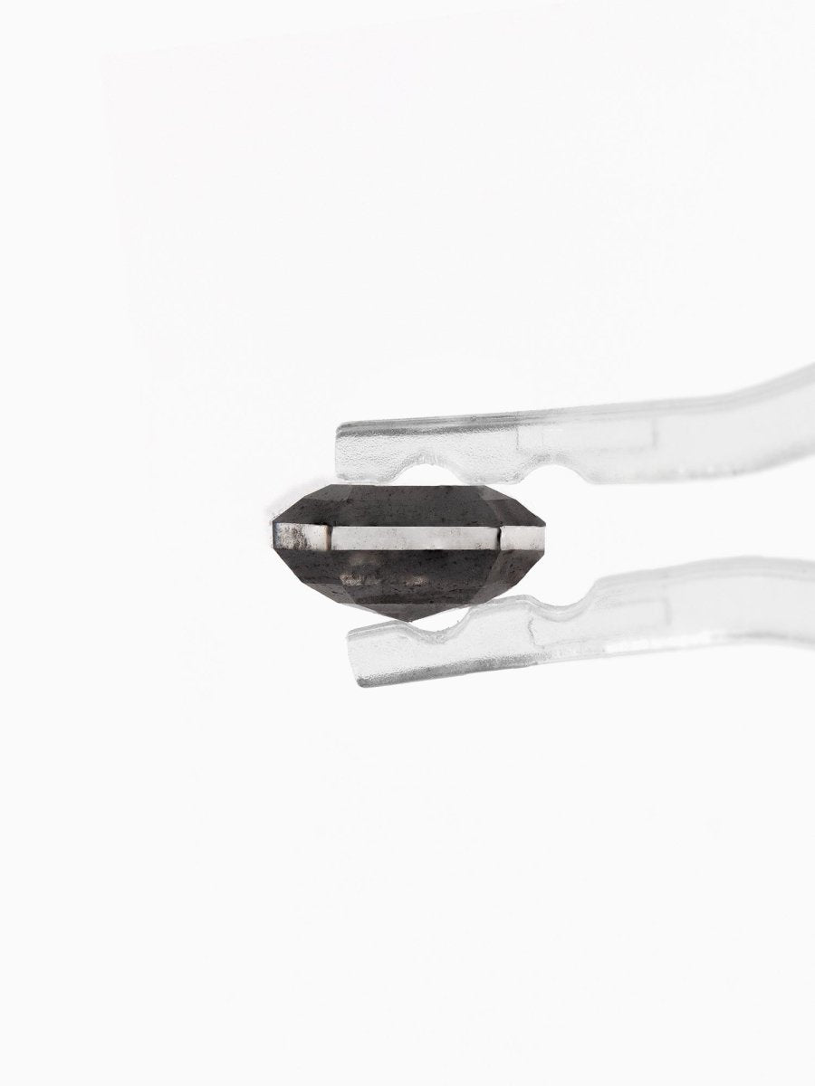 profile view of loose lab-grown emerald-cut salt pepper diamond gemstone held by tweezers