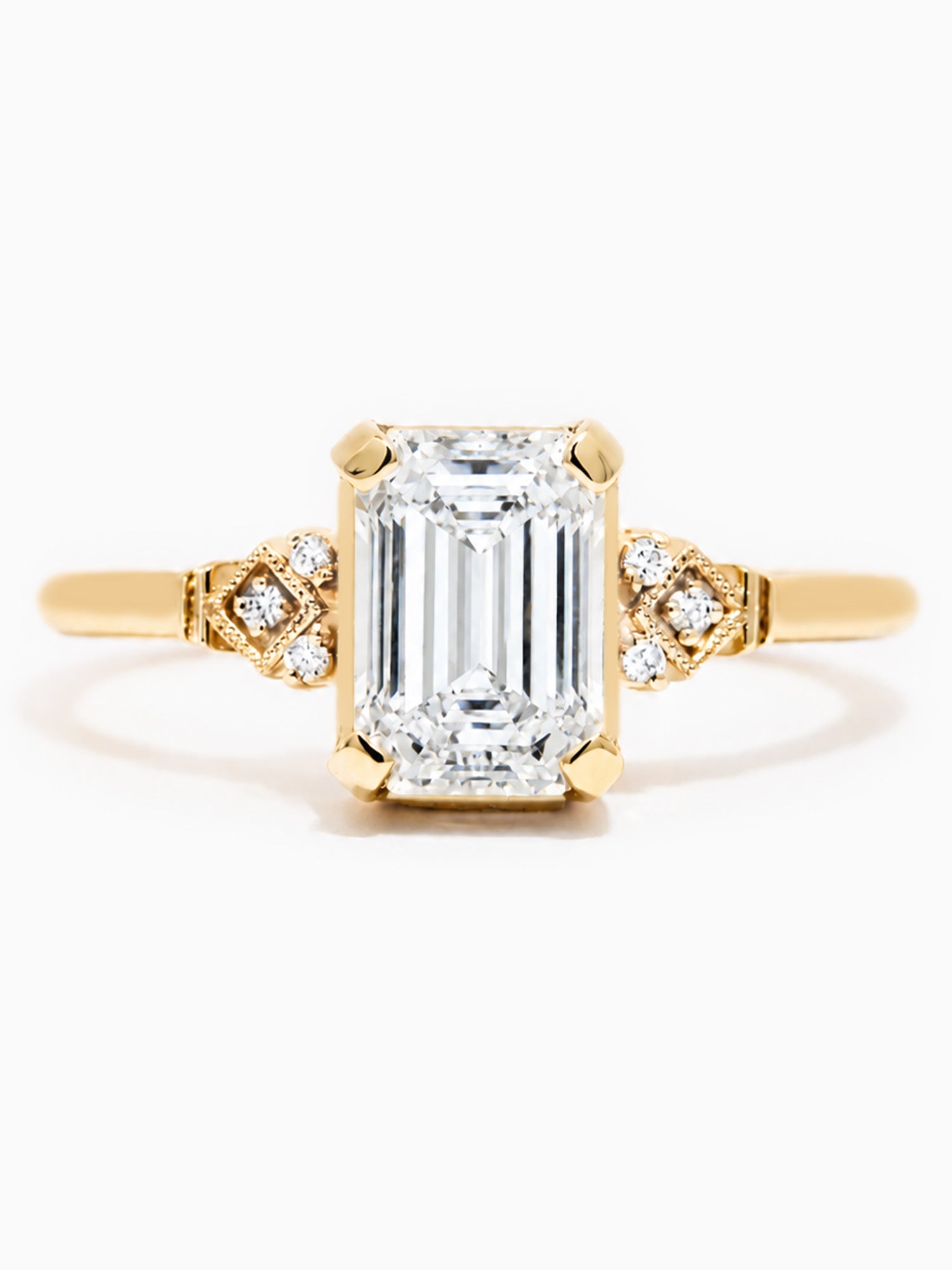 Gold ring with a large emerald-cut diamond and smaller diamonds on a white background