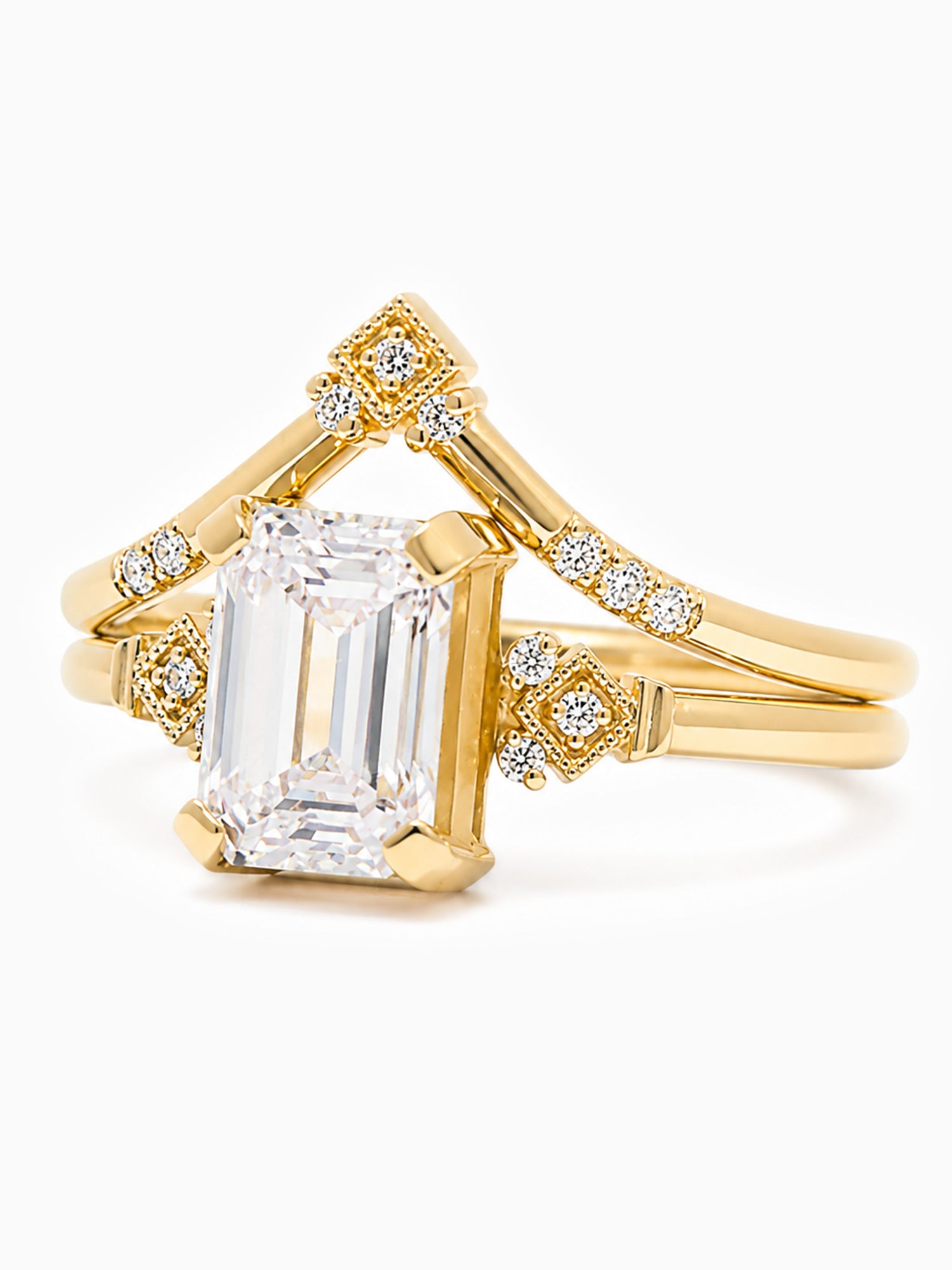 Gold ring with emerald-cut diamond and smaller diamonds on a white background