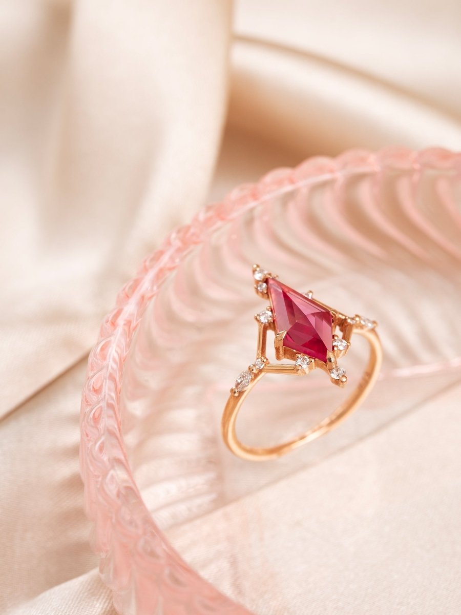 Gold ring with a red gemstone on a pink textured surface