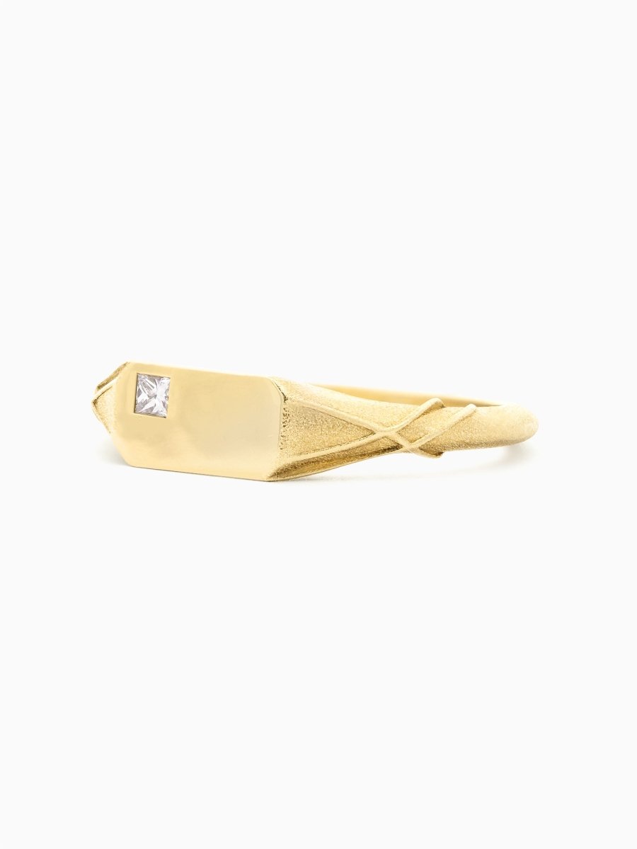 left view of gold ring with twisting organic shoulders and polished rectangular face featuring an off-center square diamond.
