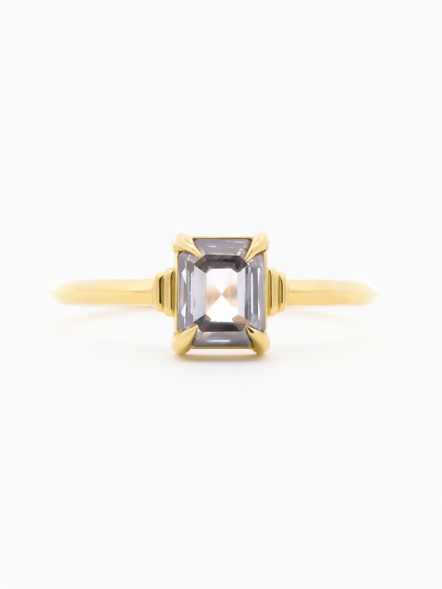 Gold ring with a emerald-cut gemstone on a white background