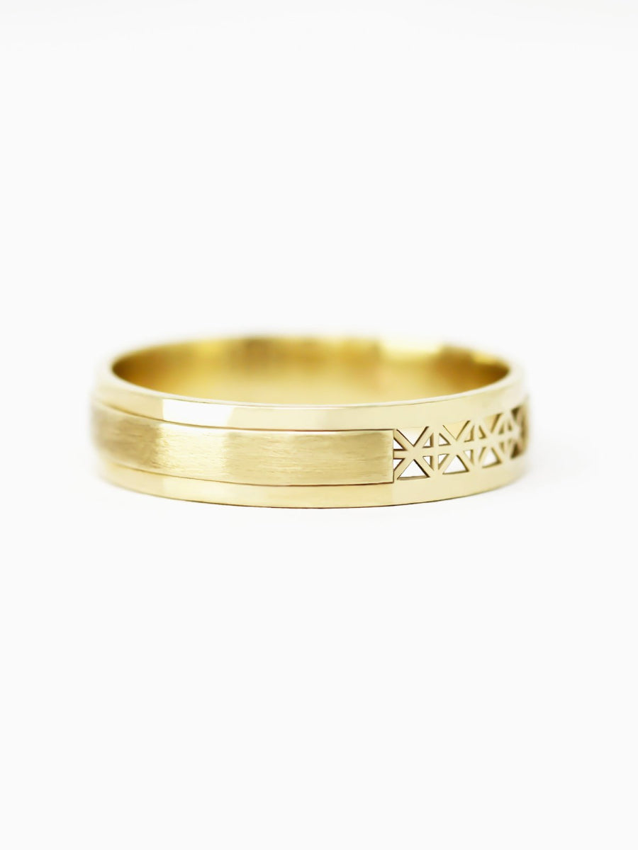 Gold ring with intricate design on a white background