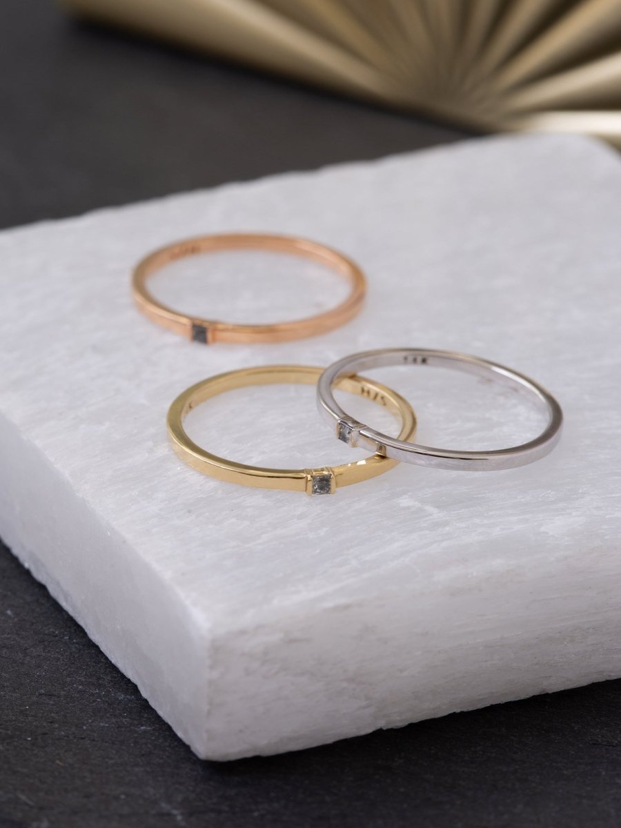 Three gold rings on a white marble surface