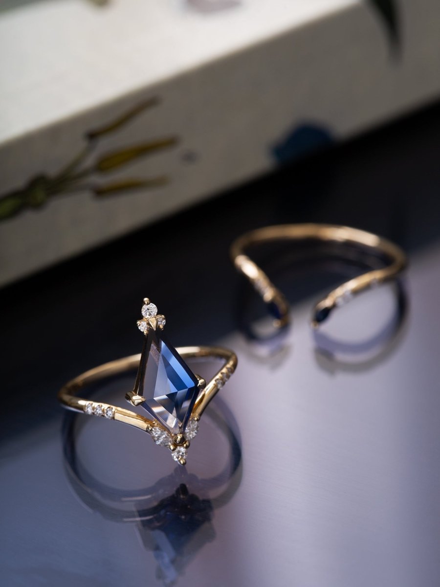 Gold ring with a blue gemstone on a reflective surface