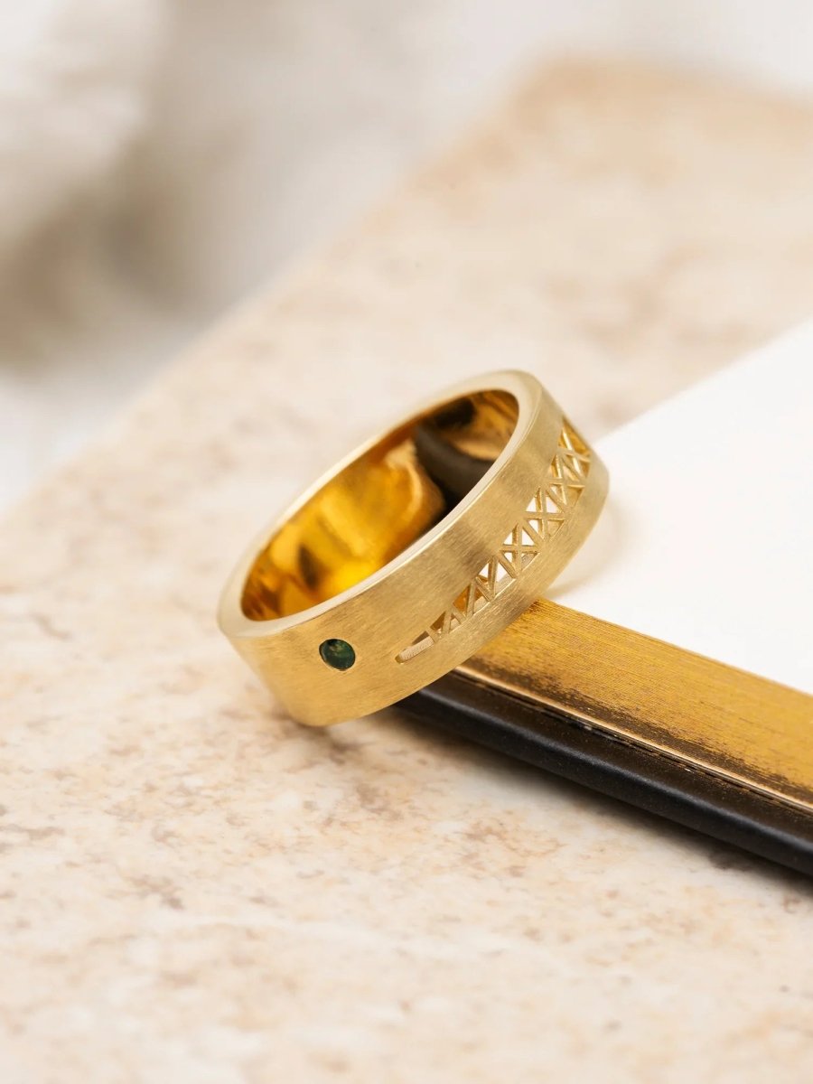 Gold ring with green gemstone on a wooden surface