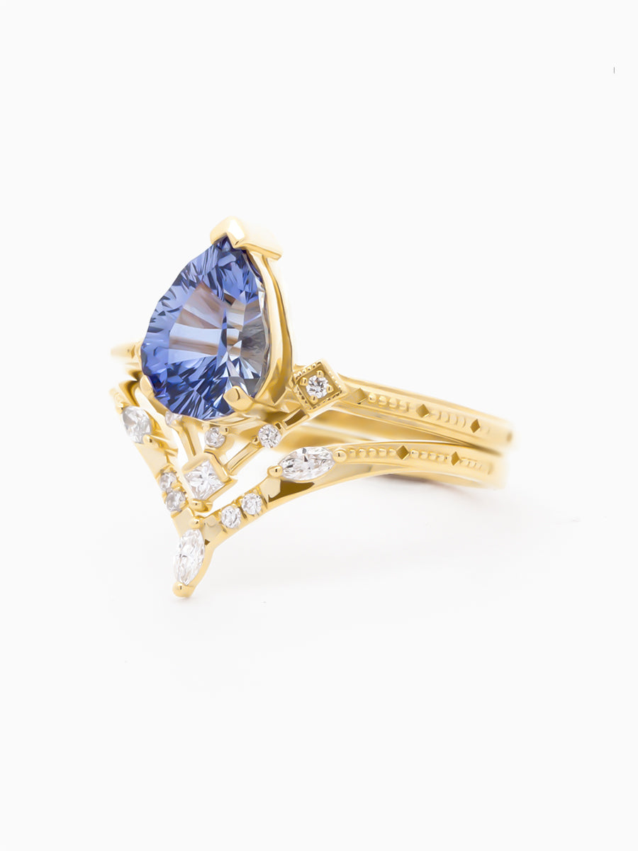 Art Deco–inspired ring with designer-cut blue pear stacked with matching chevron band, 3/4 view to show matching milgrain