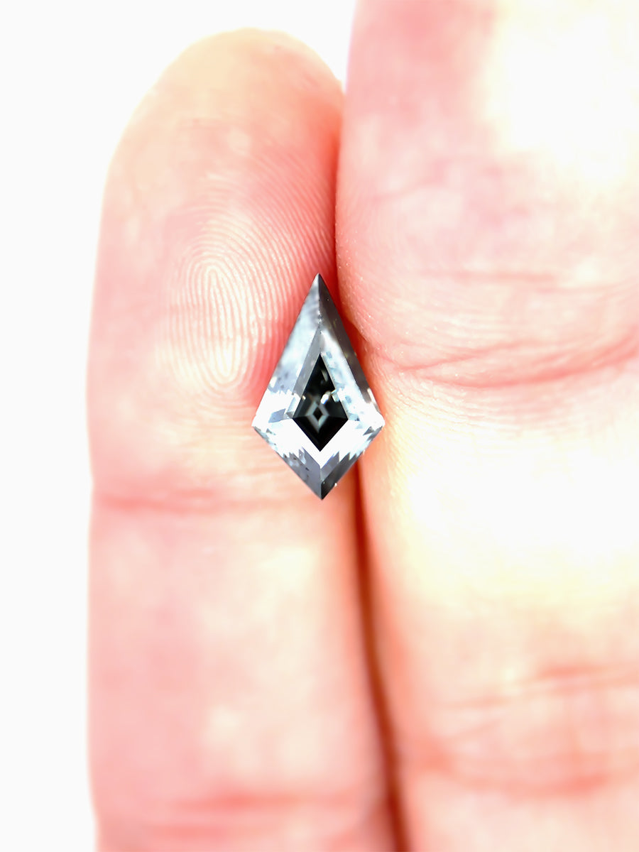 Black kite shaped moissanite placed on fingers for scale