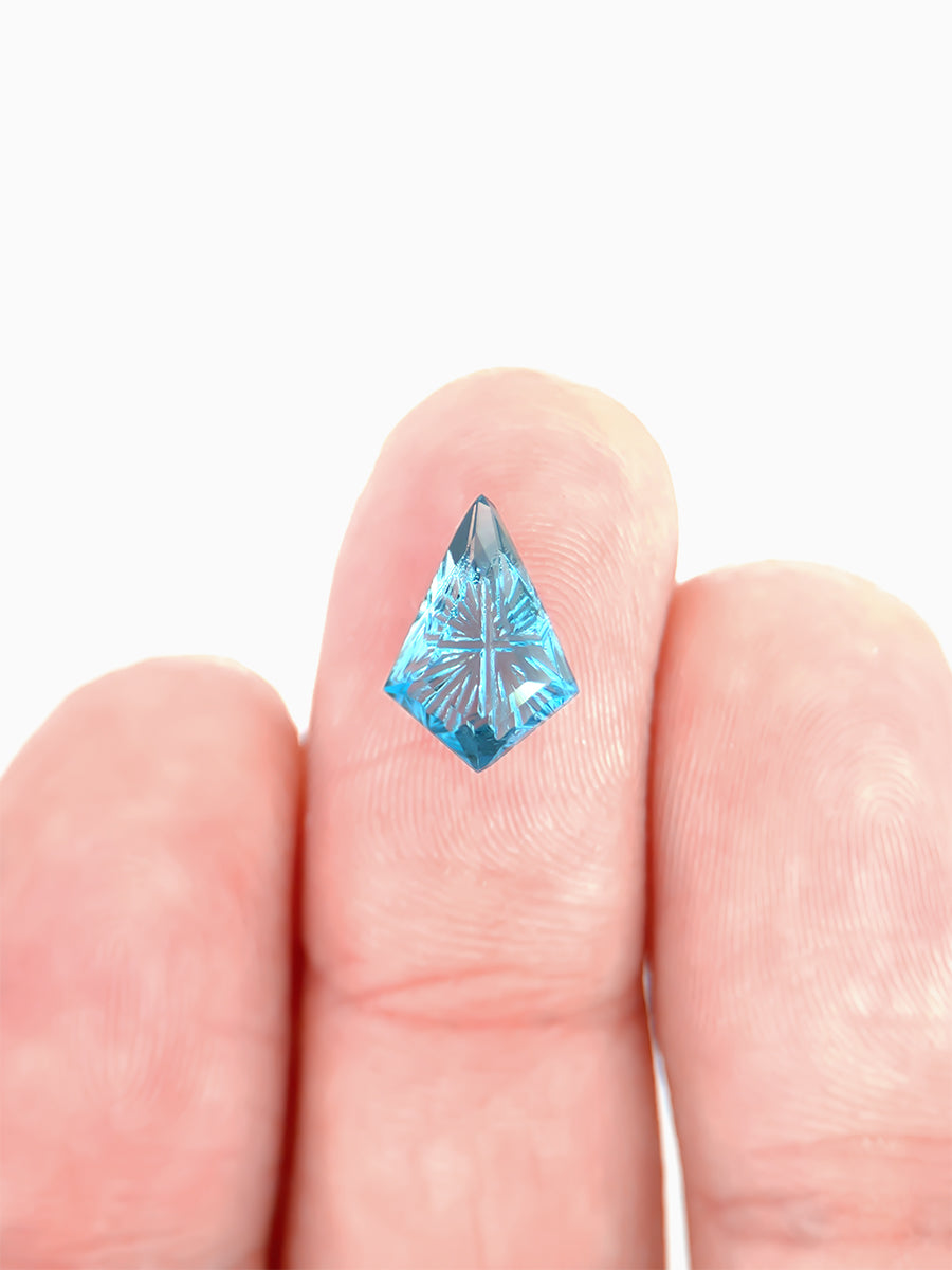 lab grown fantasy cut deep blue topaz kite on finger to show scale