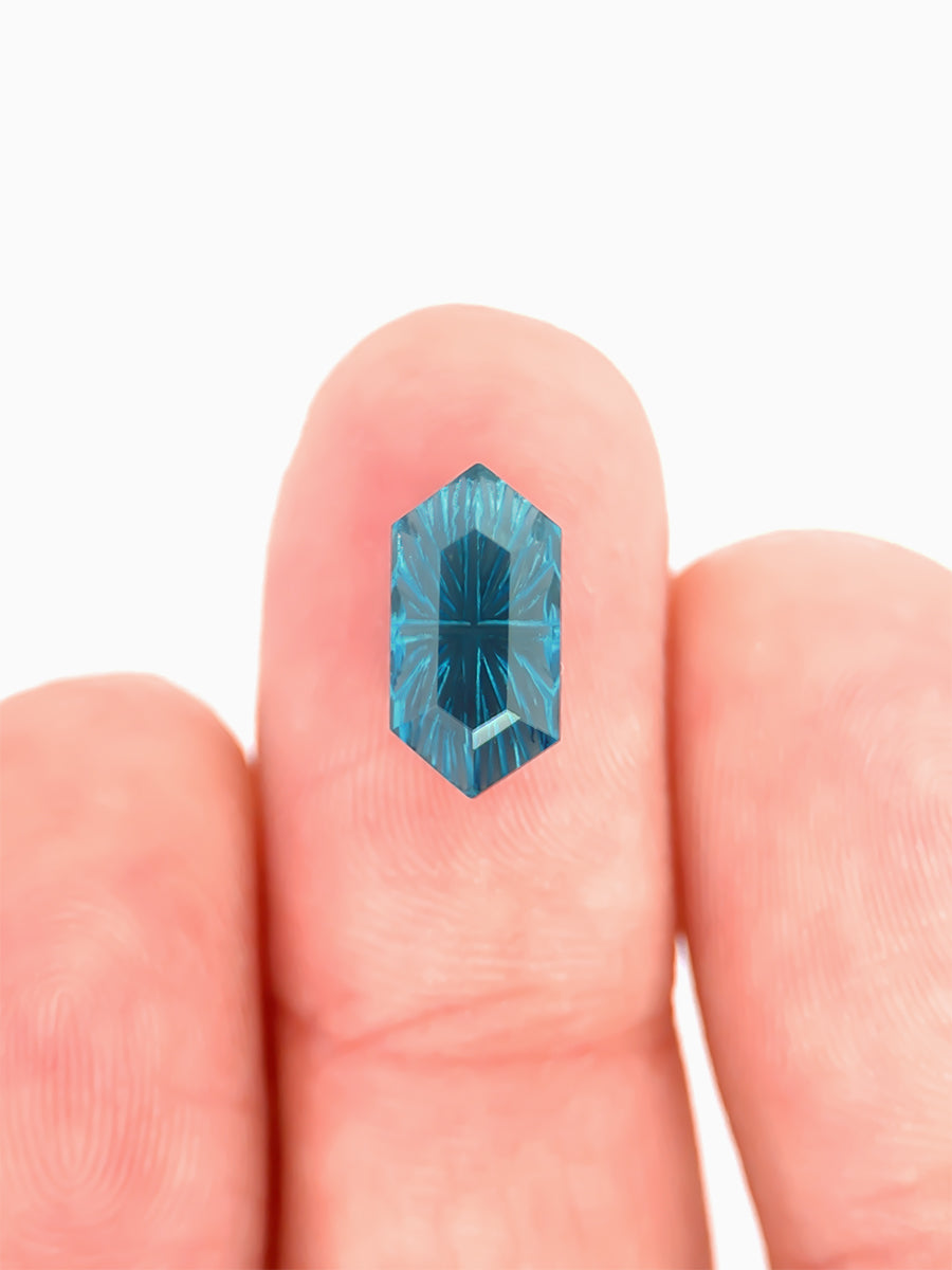 lab grown fantasy cut deep blue topaz hexagon on finger to show scale