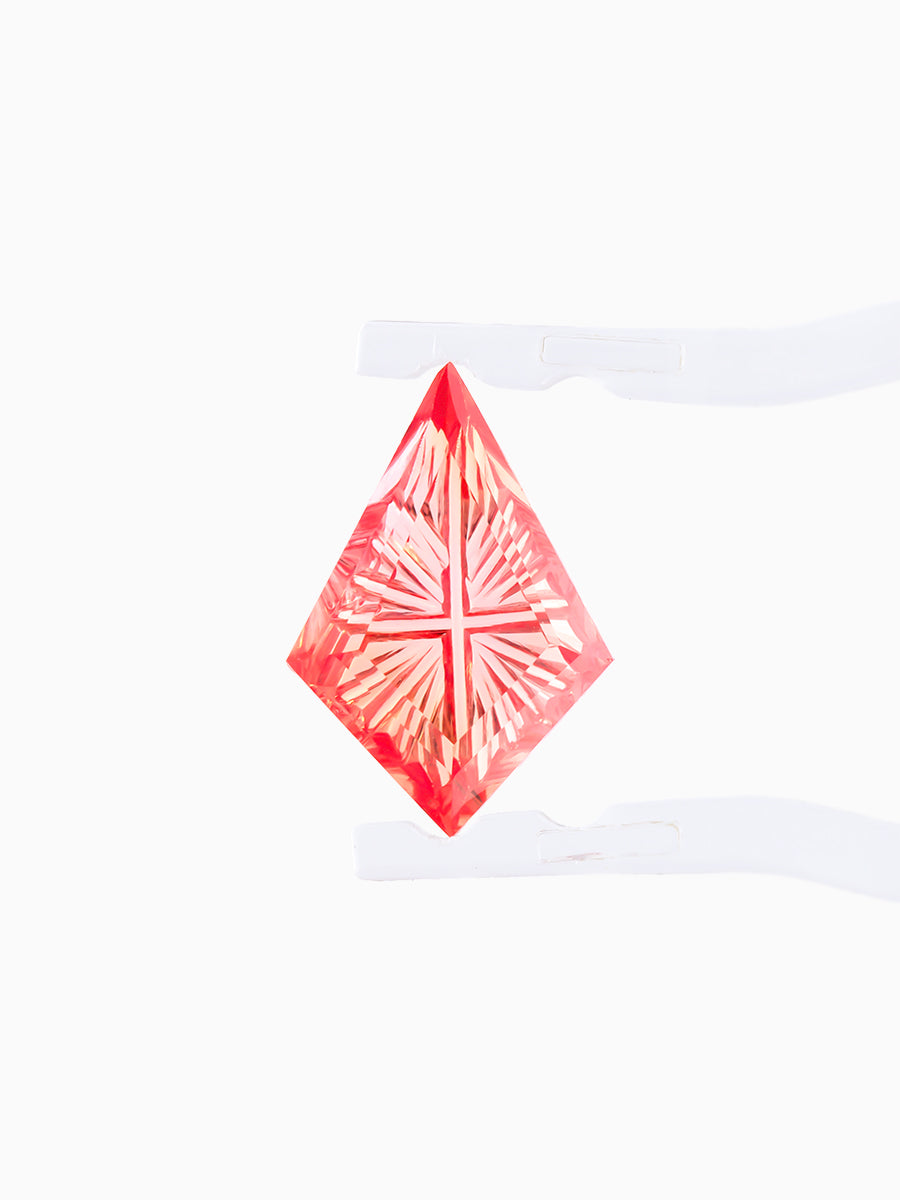 lab grown fantasy cut teal sapphire kite held by tweezers, focusing on radiating faceted pavilion