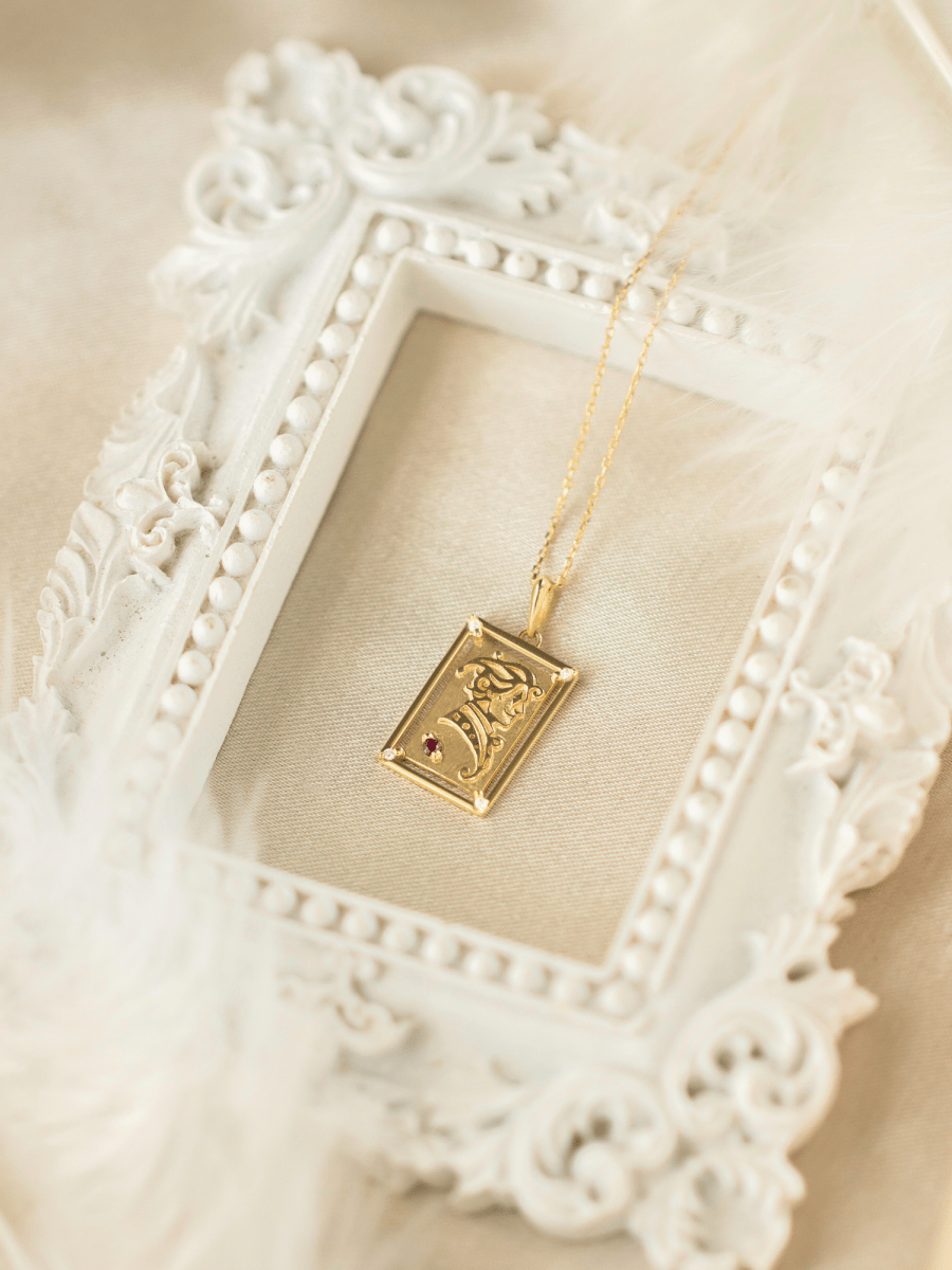 gold charm with intricately embossed gold illustration of joker card