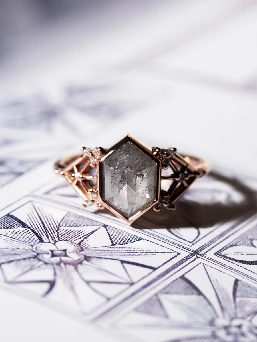 Rose gold ring with a hexagonal gemstone on a decorative card
