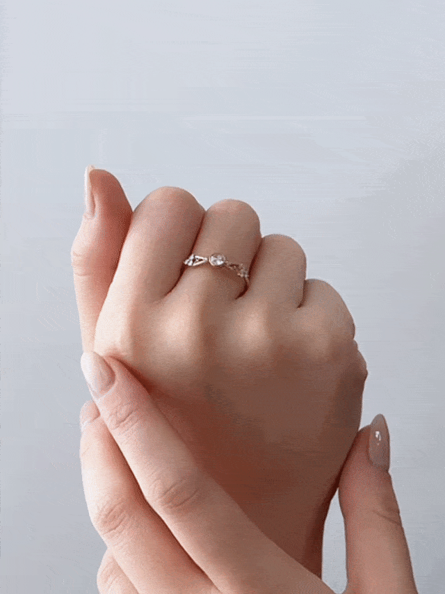 GIF of hand gently supporting another wearing petite Art Deco yellow gold ring on middle finger, turning slowly to showcase sparkle