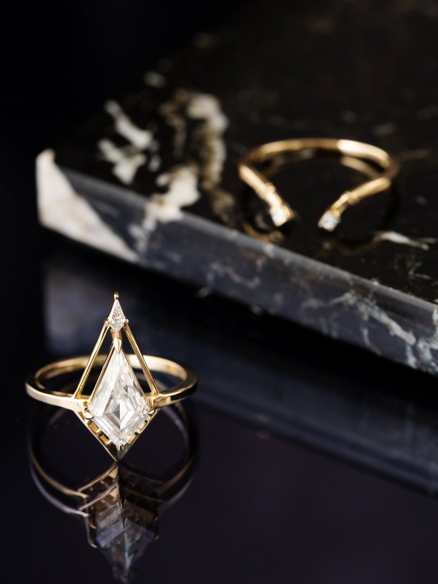 Gold Kite Deco ring with a diamond on a black marble surface