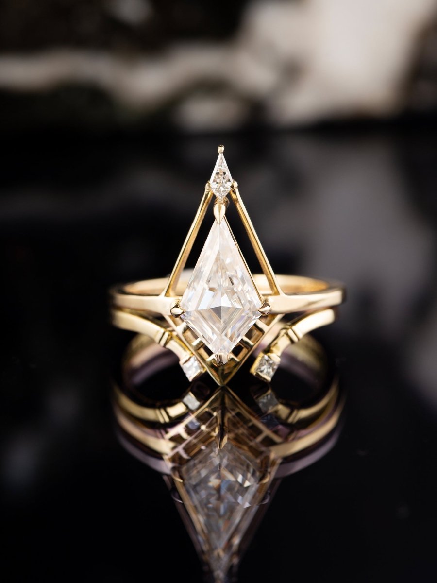 Gold Deco ring with a large diamond and smaller diamonds on a reflective surface with a dark background