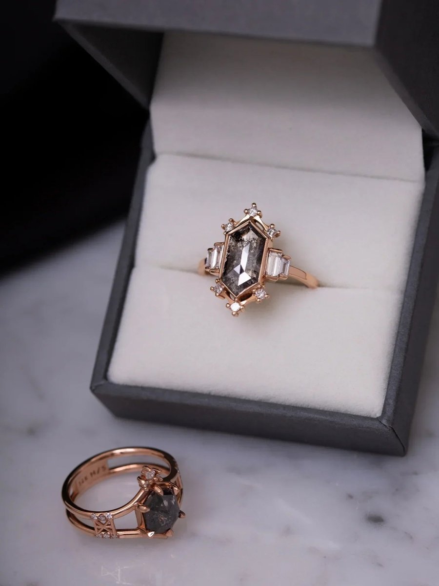 Rose gold ring with gemstone on a marble surface and in an open jewelry box.
