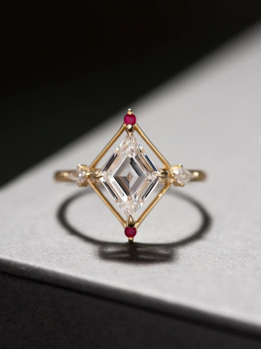 Gold ring with diamond-shaped gemstones and red stones on a dark surface