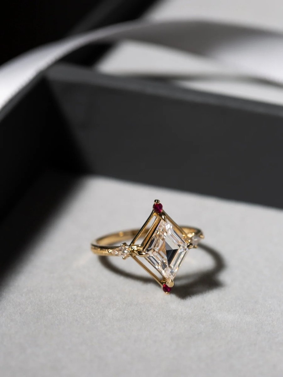 Gold ring with a large diamond and smaller stones on a light gray surface