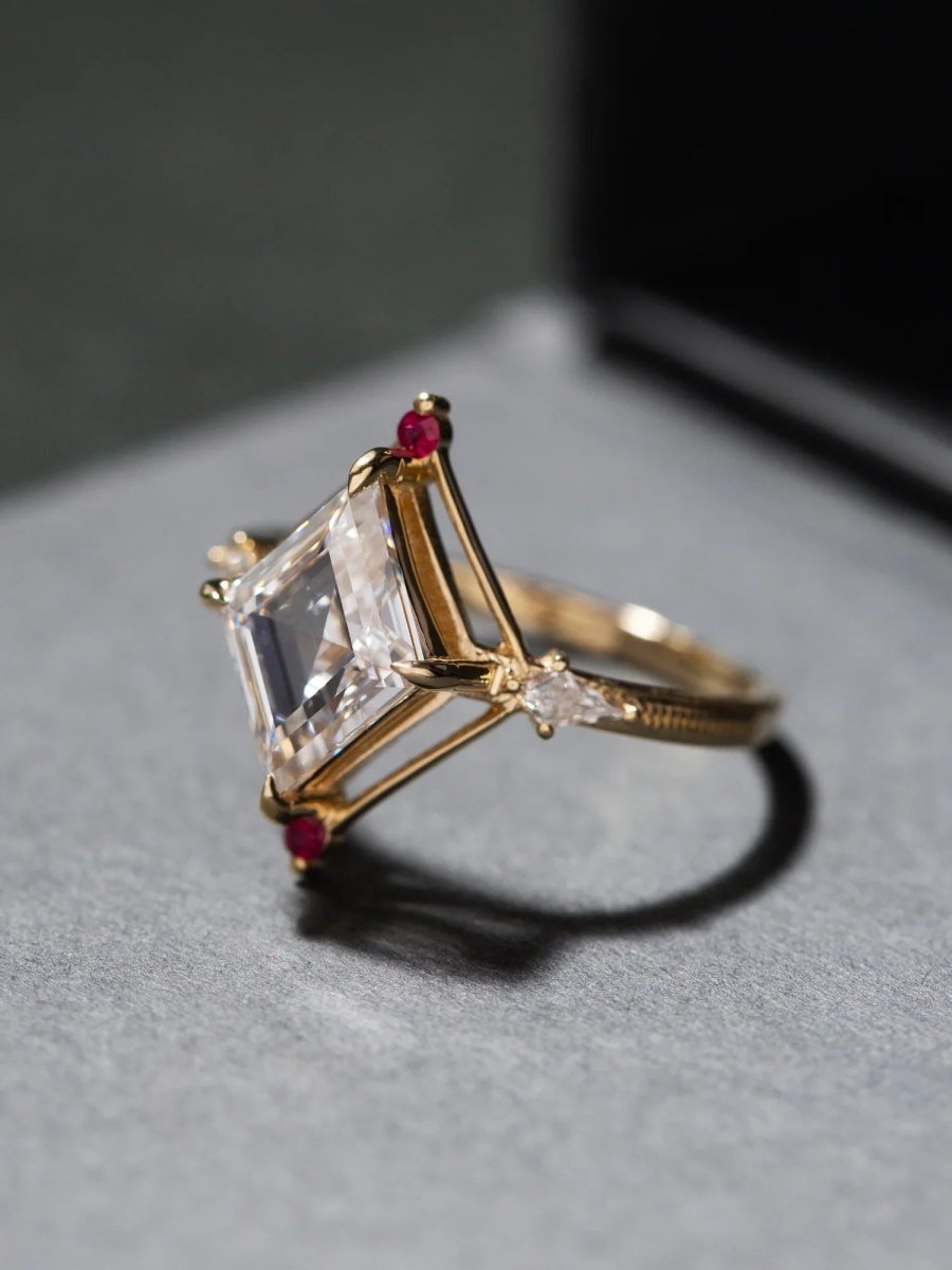 Gold ring with a large rectangular gemstone and smaller red stones on a gray surface