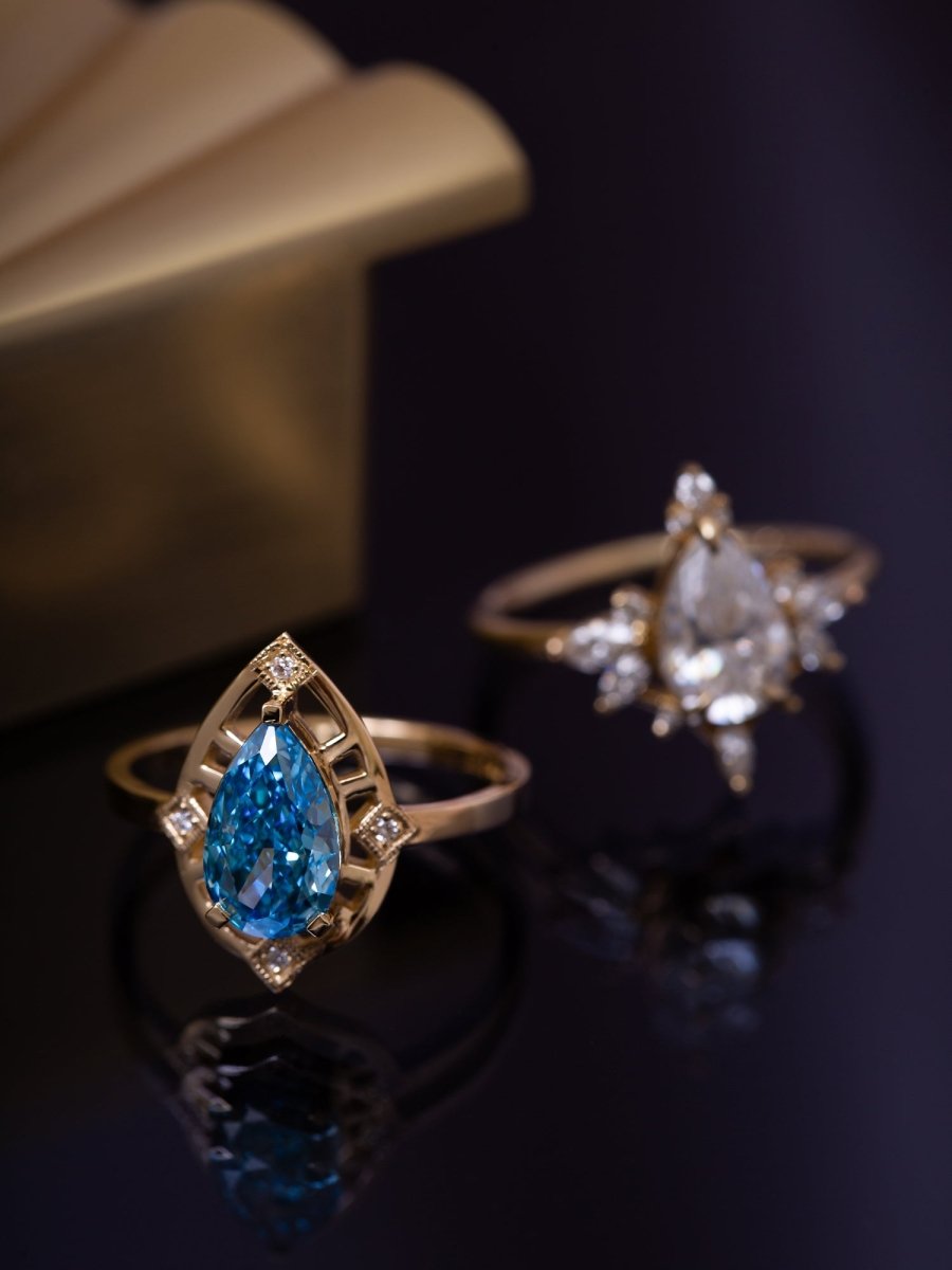 Two gold rings with gemstones on a dark surface