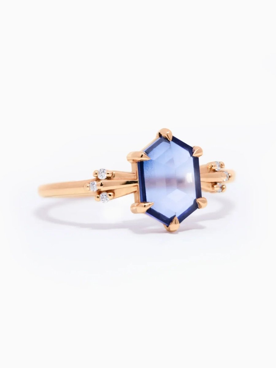 Gold ring with a blue gemstone on a white background