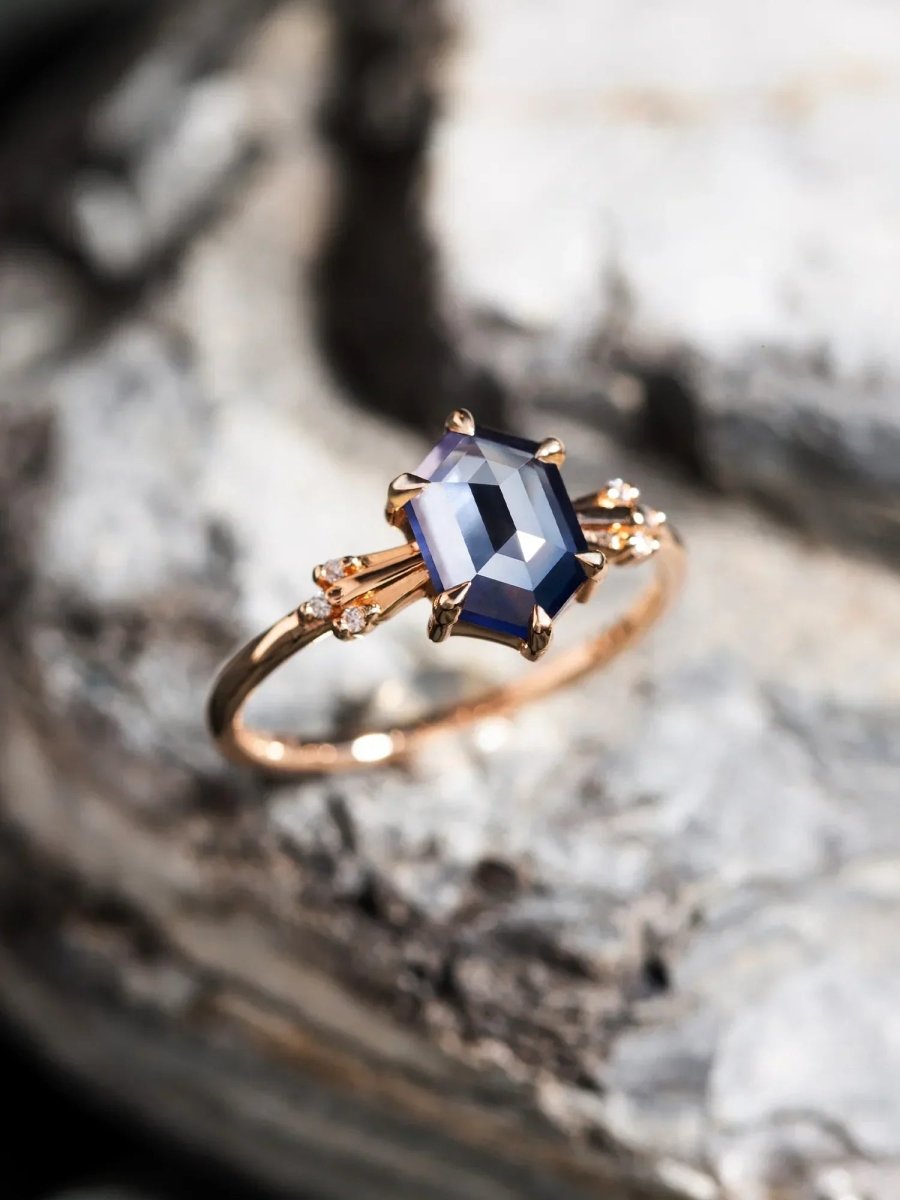 Rose gold ring with a blue gemstone on a blurred background
