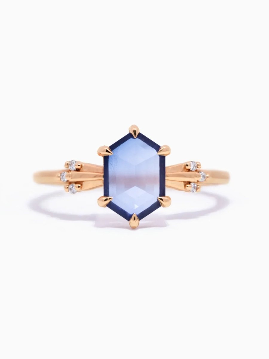 Rose gold ring with a blue gemstone on a white background
