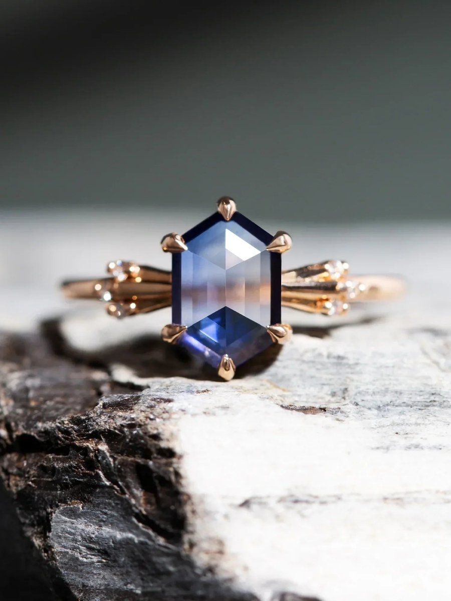 Rose gold ring with a large blue gemstone on a textured surface