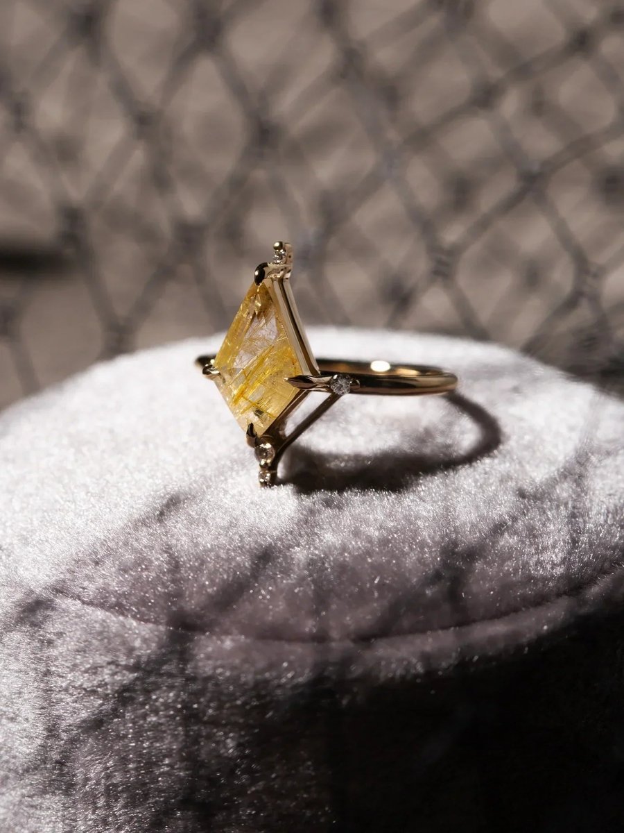 Gold ring with a yellow gemstone on a textured surface