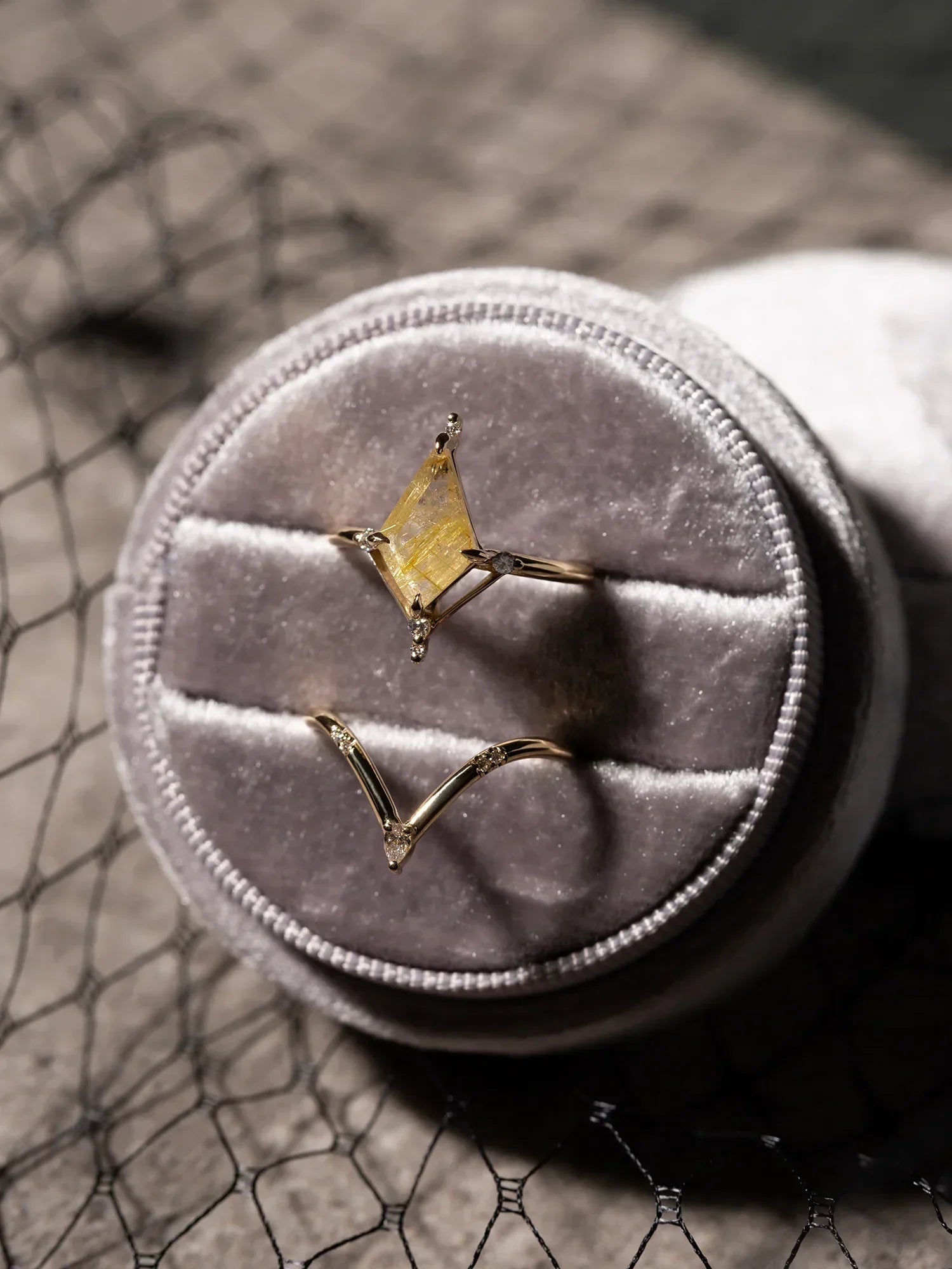 Gold ring with a yellow gemstone on a gray velvet cushion