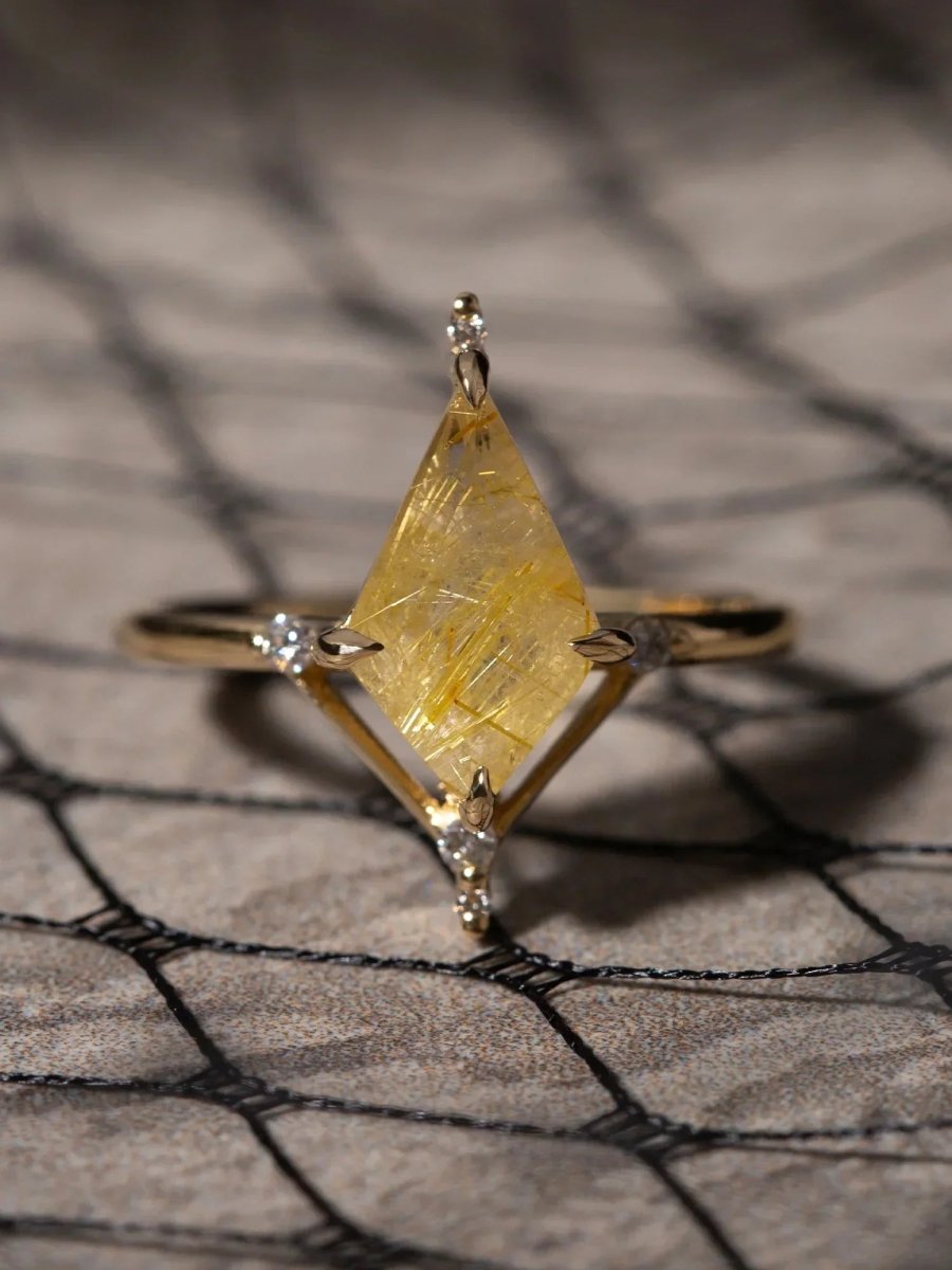 Gold ring with a large yellow crystal and smaller crystals on a textured surface